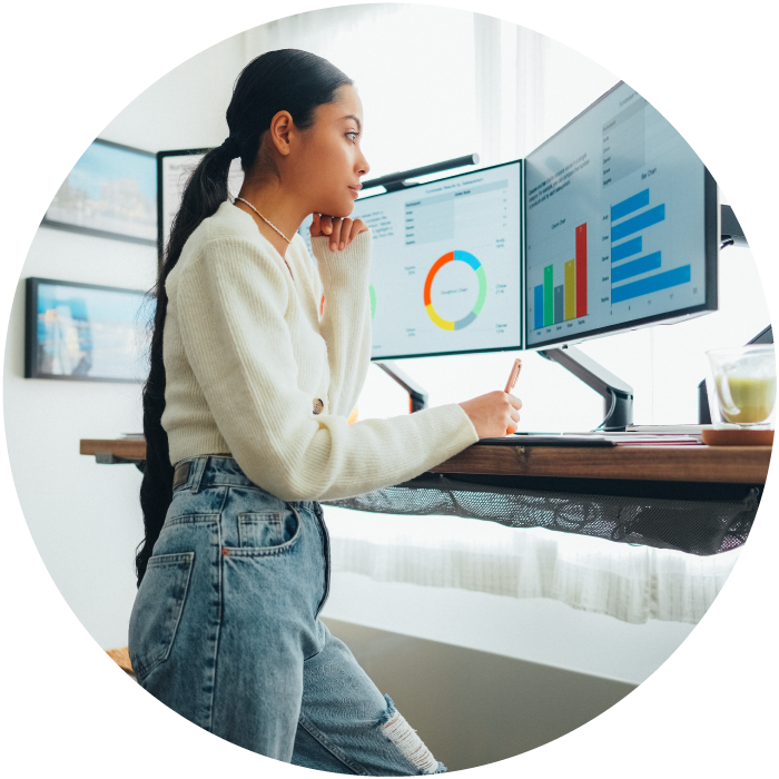 Woman at stand up desk looking at monitors