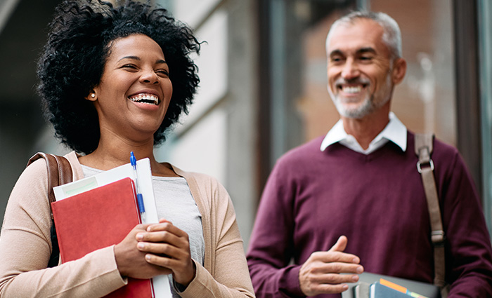 Woman and Man holding book and laptop smiling